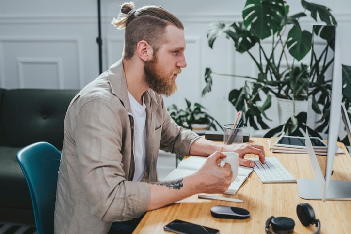 Мужчина с топ-нотом работает за компьютером