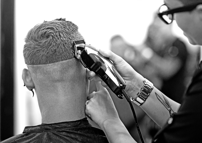 Барбер делает фейд машинкой клиенту в салоне