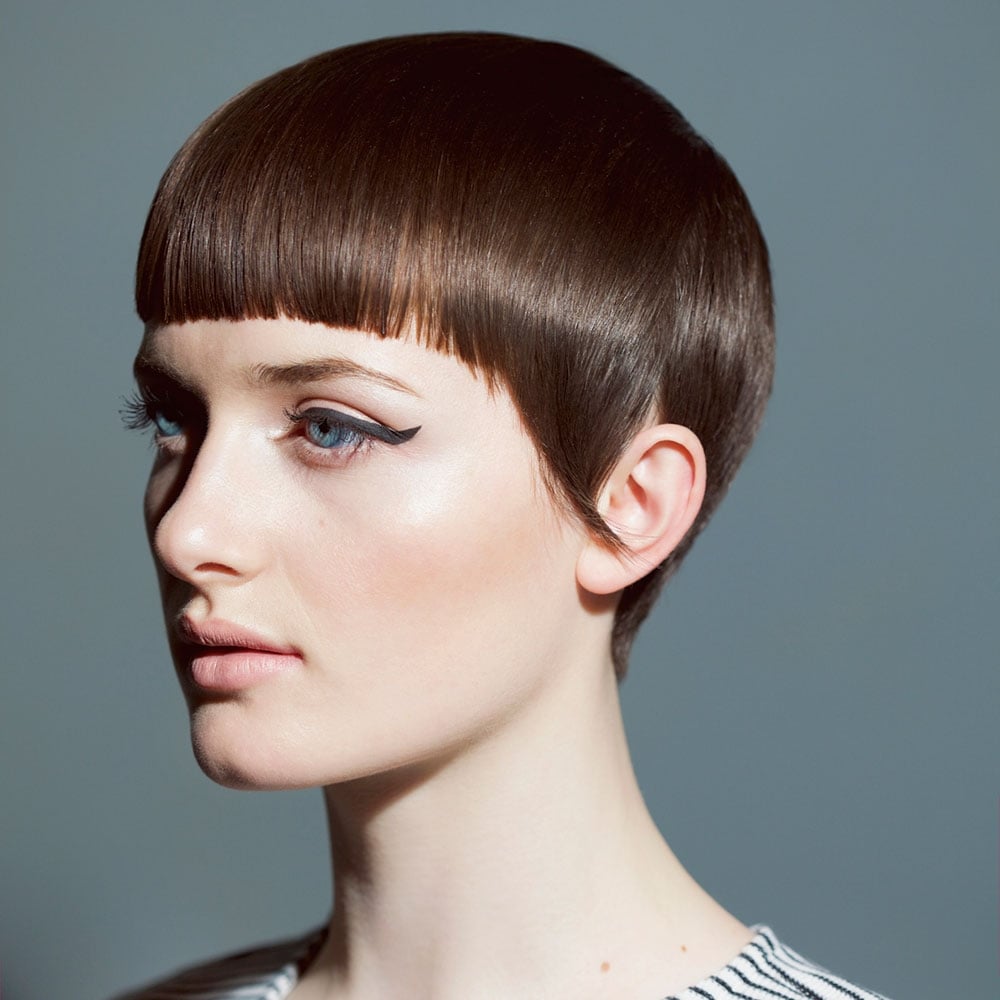 Короткая арочная челка на темных волосах в сочетании с графичным макияжем глаз